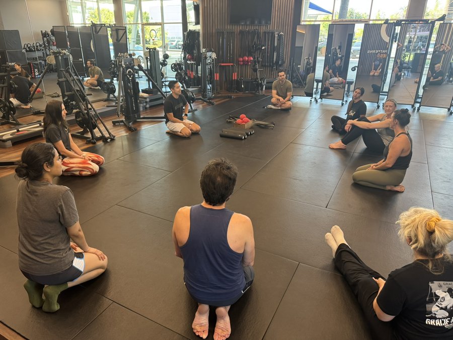 A small group seated on the mats during a Functional Patterns class at FP Costa Mesa
