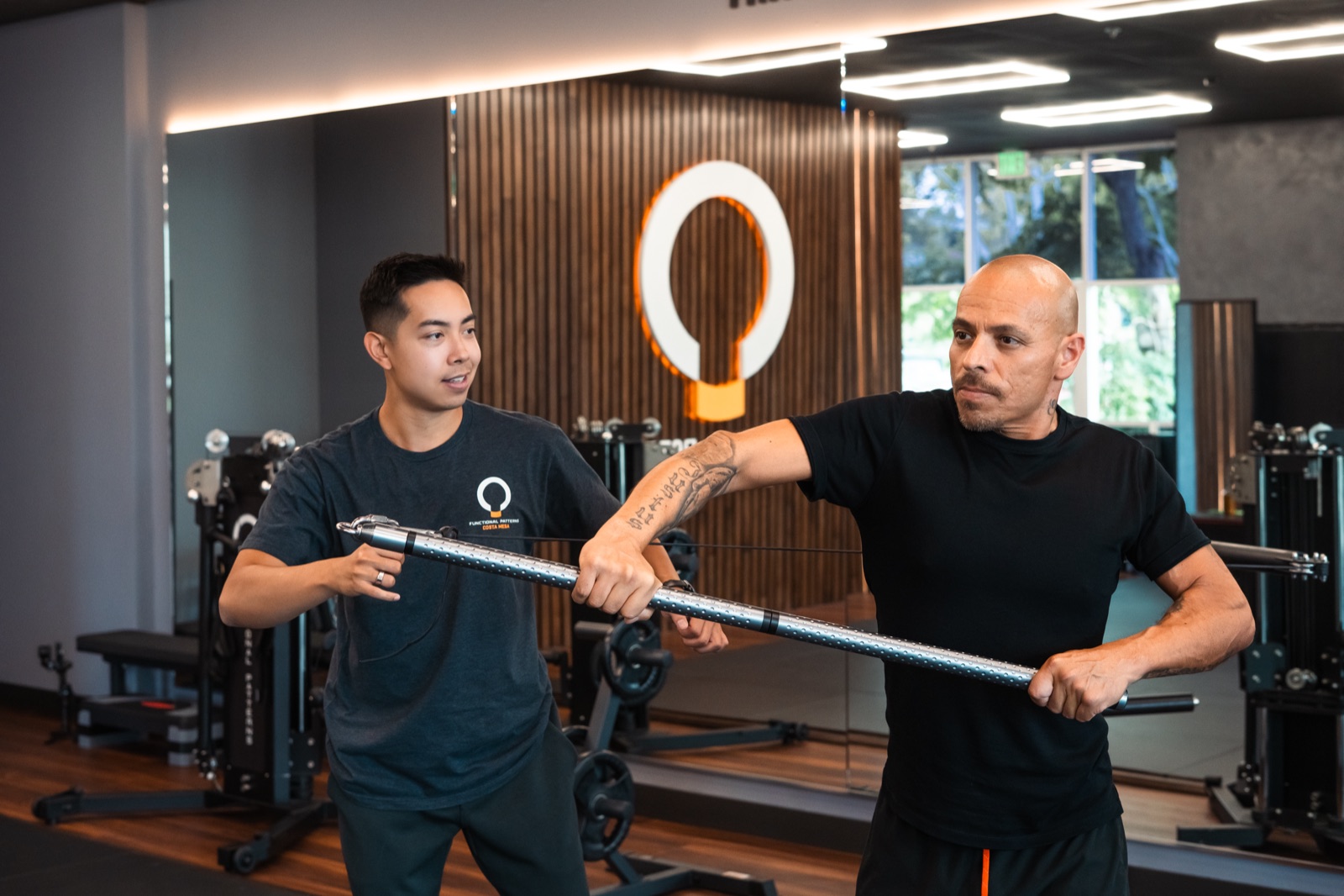 A Functional Patterns coach guiding a client through an RG Bar exercise during a one-on-one session at FP Costa Mesa